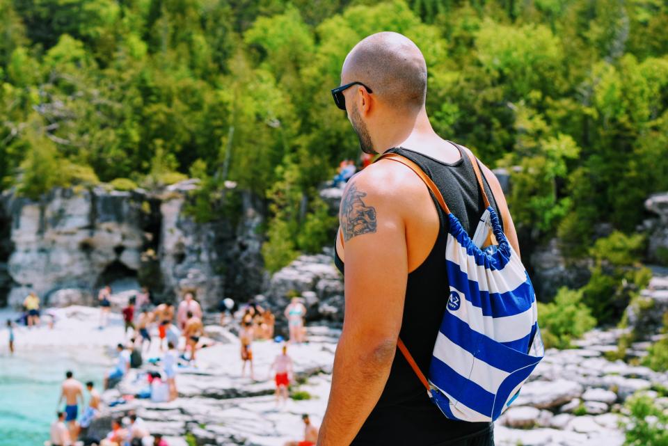 Digital nomad with backpack and laptop, surrounded by travel gear on a tropical beach